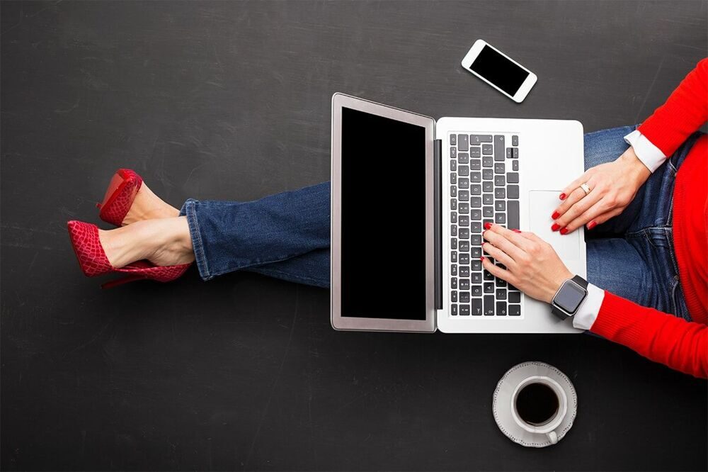 Woman-sitting-on-ground-at-the-office-with-computer-in-her-lap-1-min